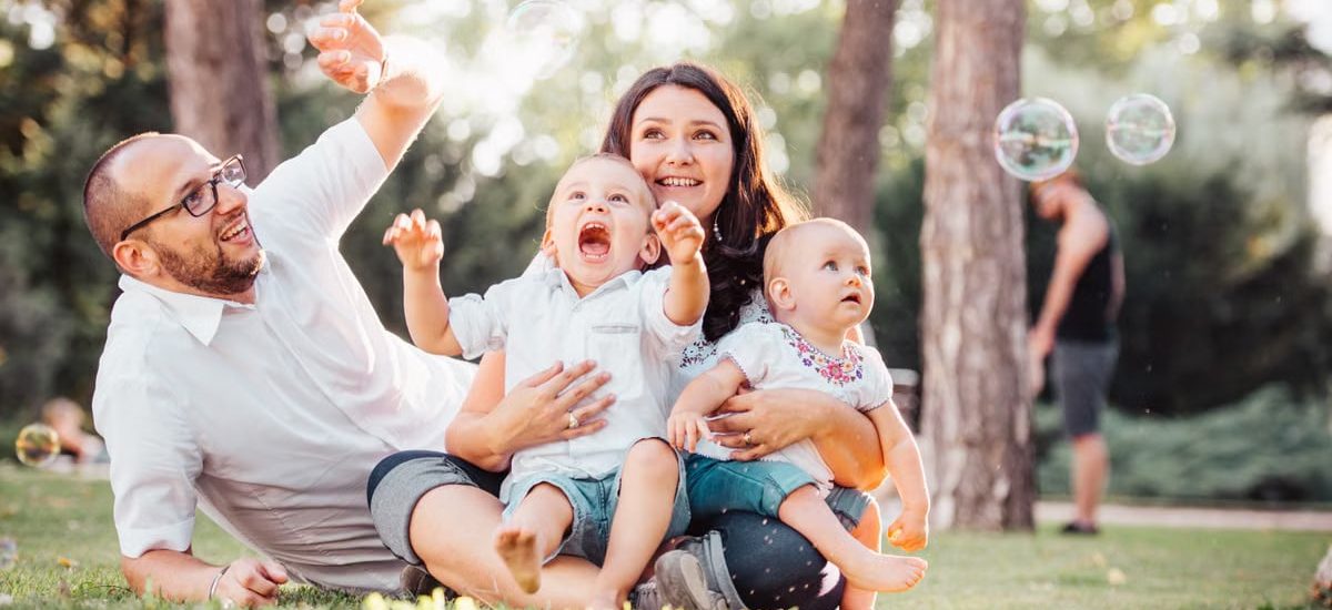 Joyful family enjoying a sunny day in the park while playing with bubbles.